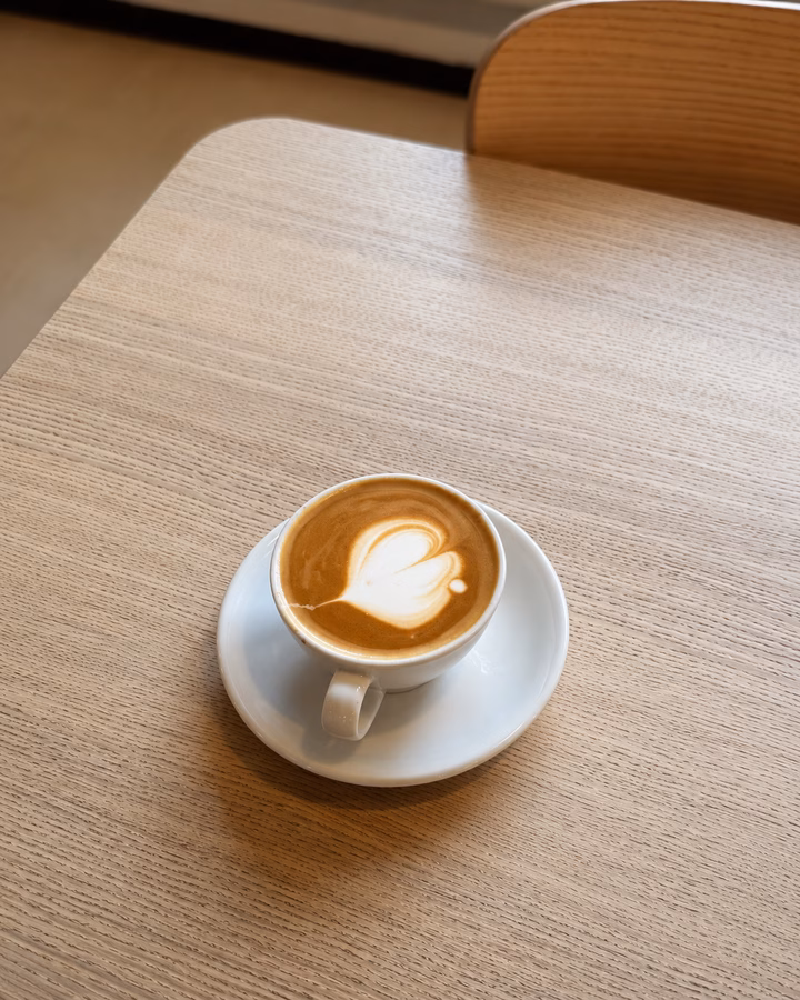Flat White mit Latte Art auf Holztisch